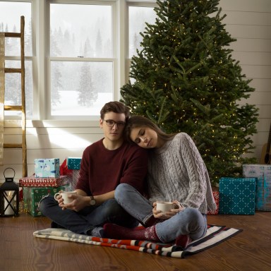 couple cuddling by tree with warm drinks