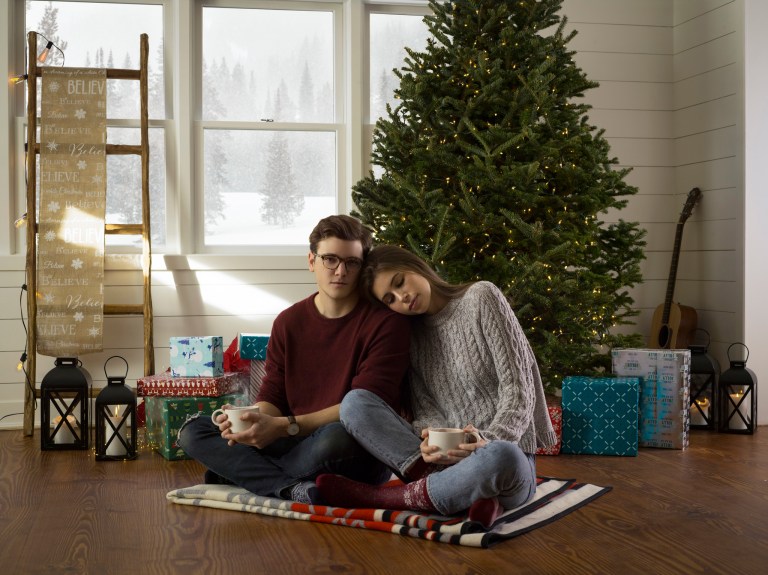 couple cuddling by tree with warm drinks
