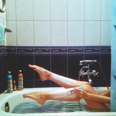 girl shaving her legs in bath tub