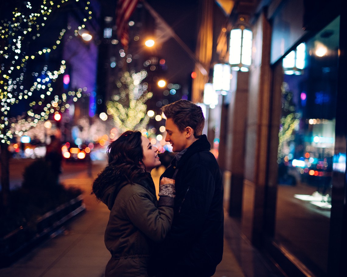 guy and girl about to kiss outside christmas lights