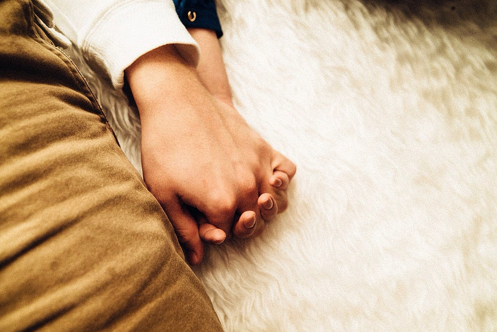 couple holding hands on white rug