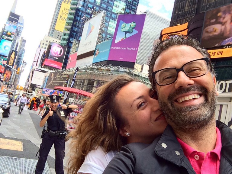 happy couple taking selfie in NYC with cop photobombing