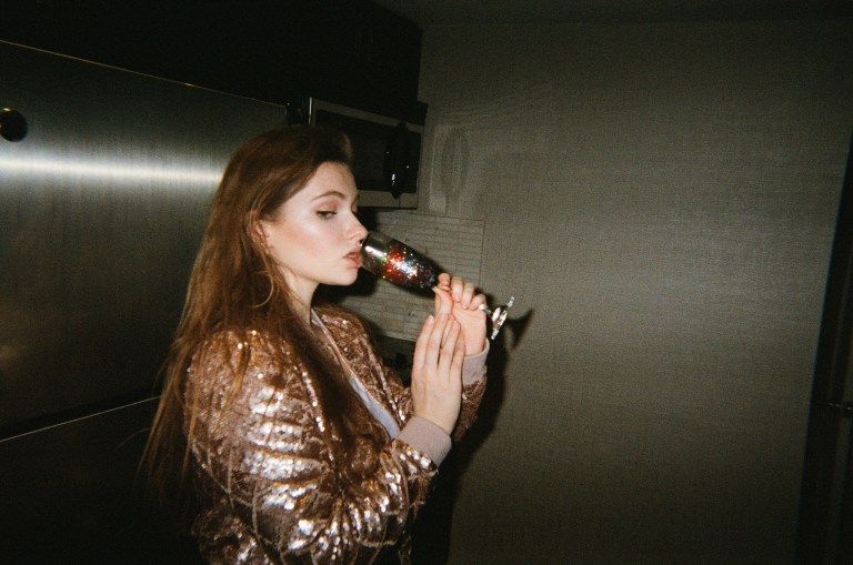 girl in gold jacket drinking champagne