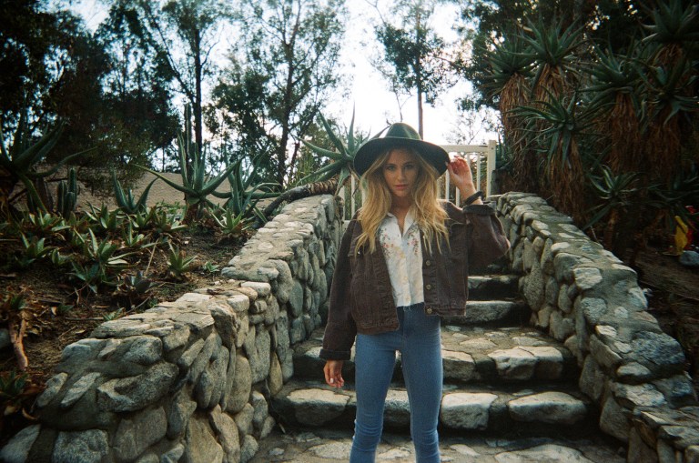 Cool girl in a large hat standing on stone steps outdoors