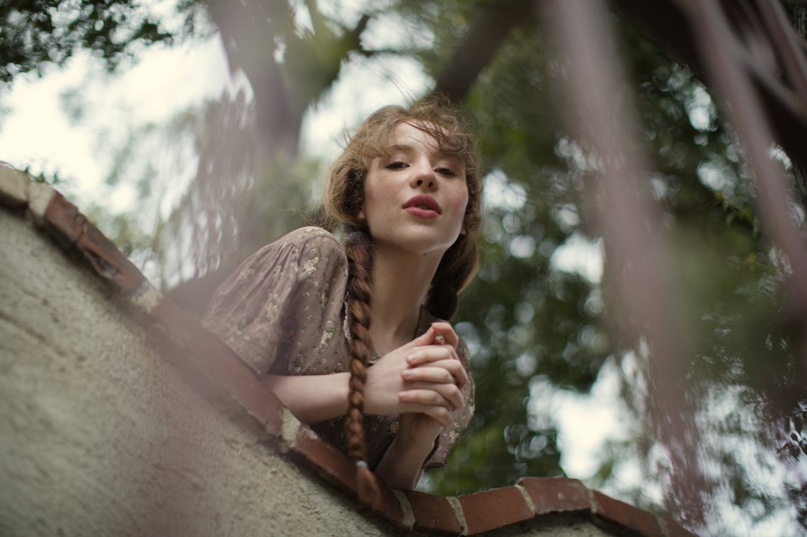 Lovely girl in braids looks down from the castle wall like Juliet Capulet