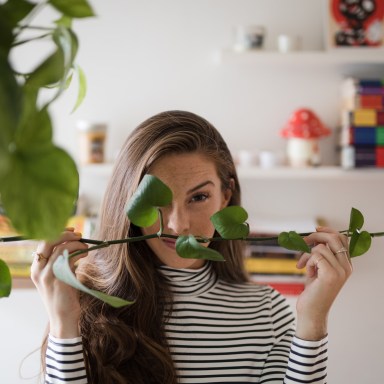 girl hiding behind stem of leaves