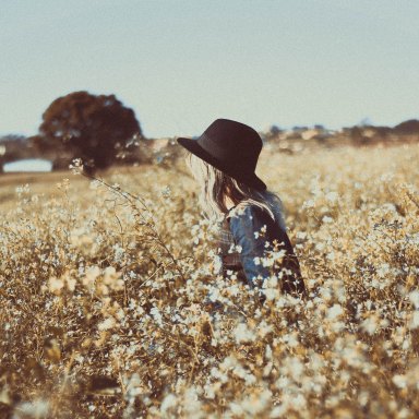 a girl in a hat in a field of flowers