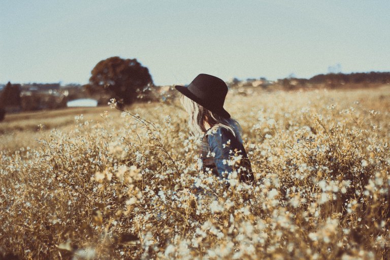 a girl in a hat in a field of flowers