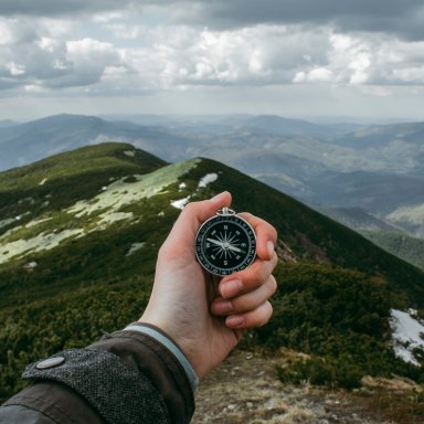Person stares at a compass while looking out into the great unknown