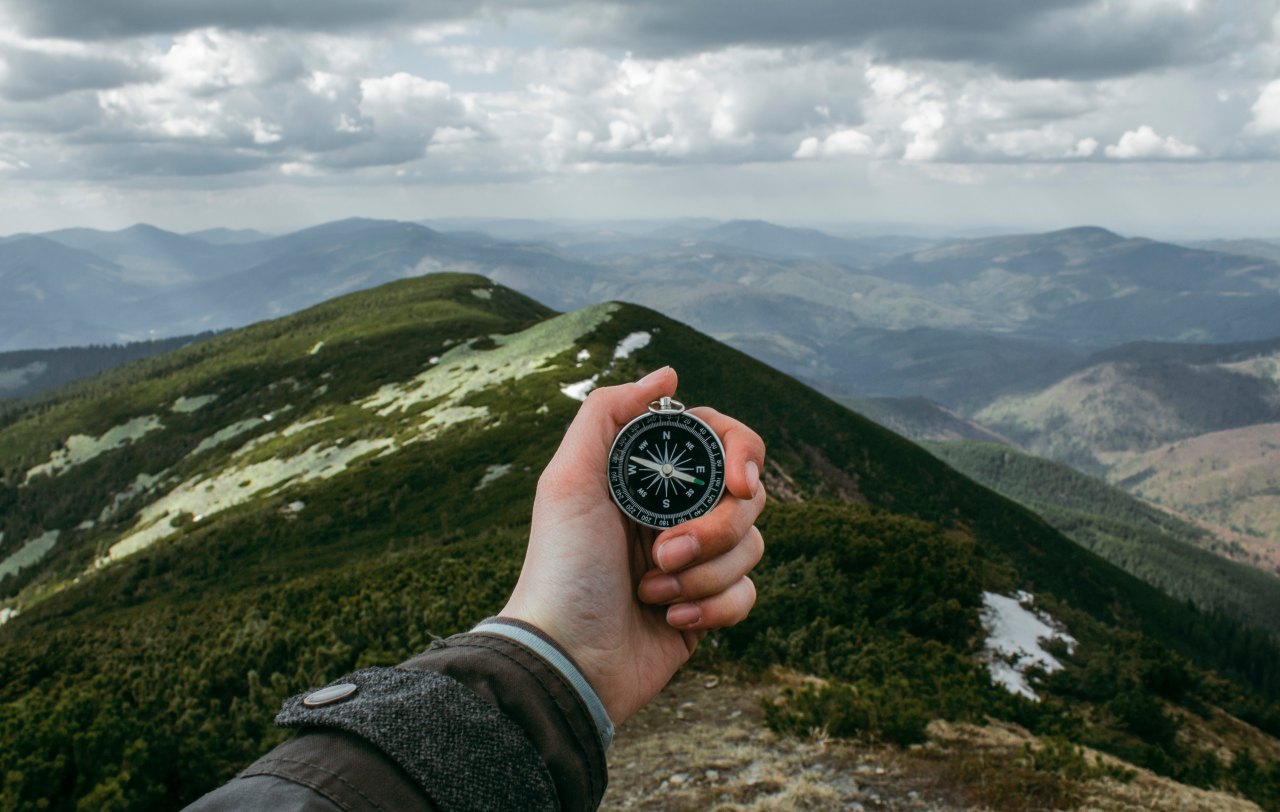 Person stares at a compass while looking out into the great unknown