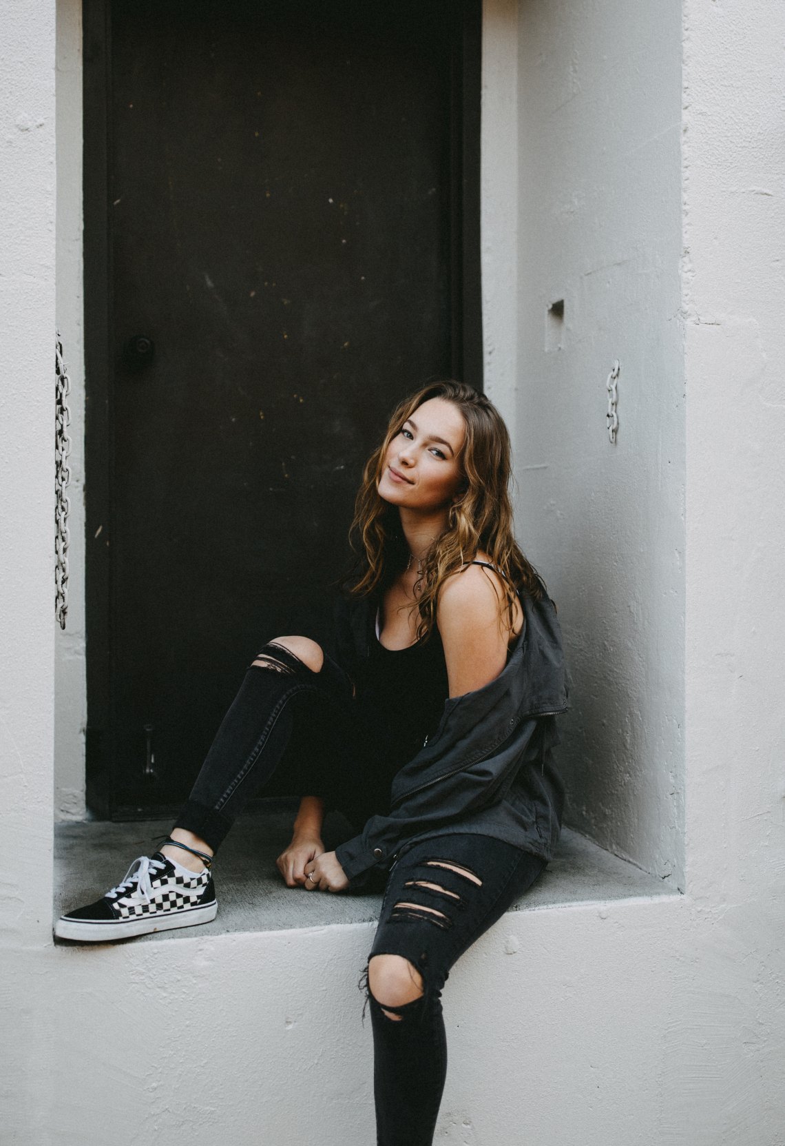 girl in ripped jeans sitting in an alcove