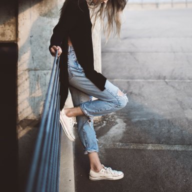 woman leaning against post with ripped jeans