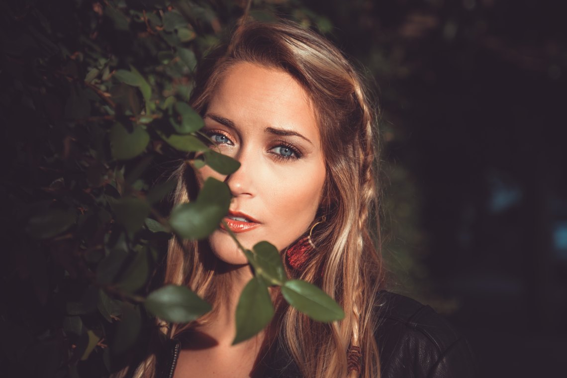 girl standing behind tree