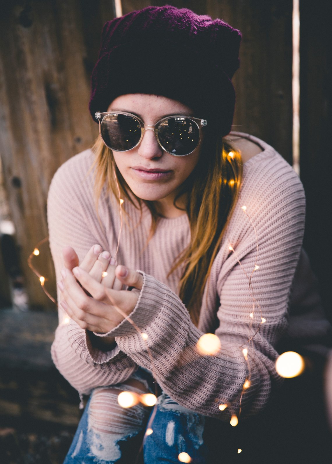 girl in a sweater with sunglasses and twinkle lights