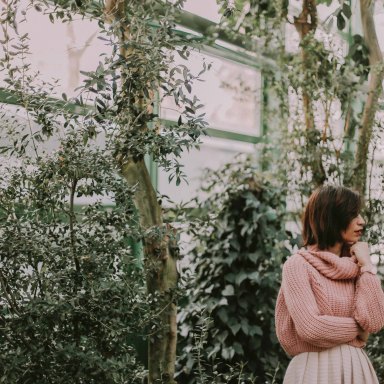 woman in a pink sweater in a greenhouse