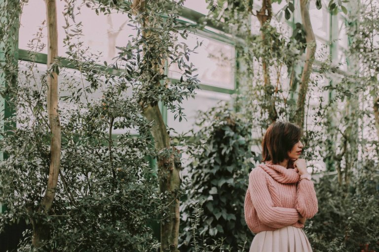 woman in a pink sweater in a greenhouse