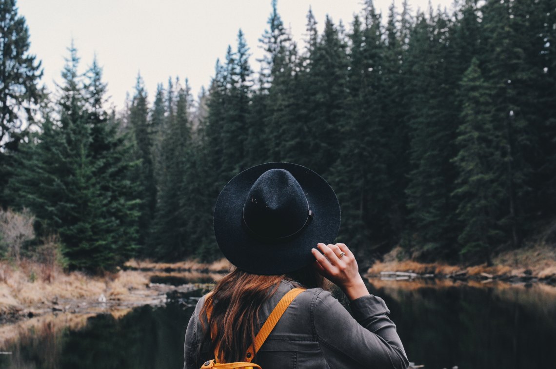 woman wandering through the forest in her hat