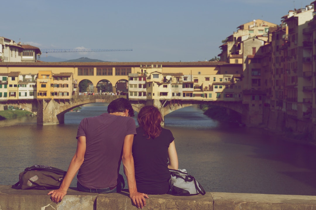 Couple sitting closely together on a ledge overlooking a river