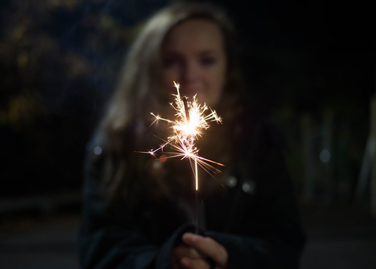 girl holding a sparkler backlit