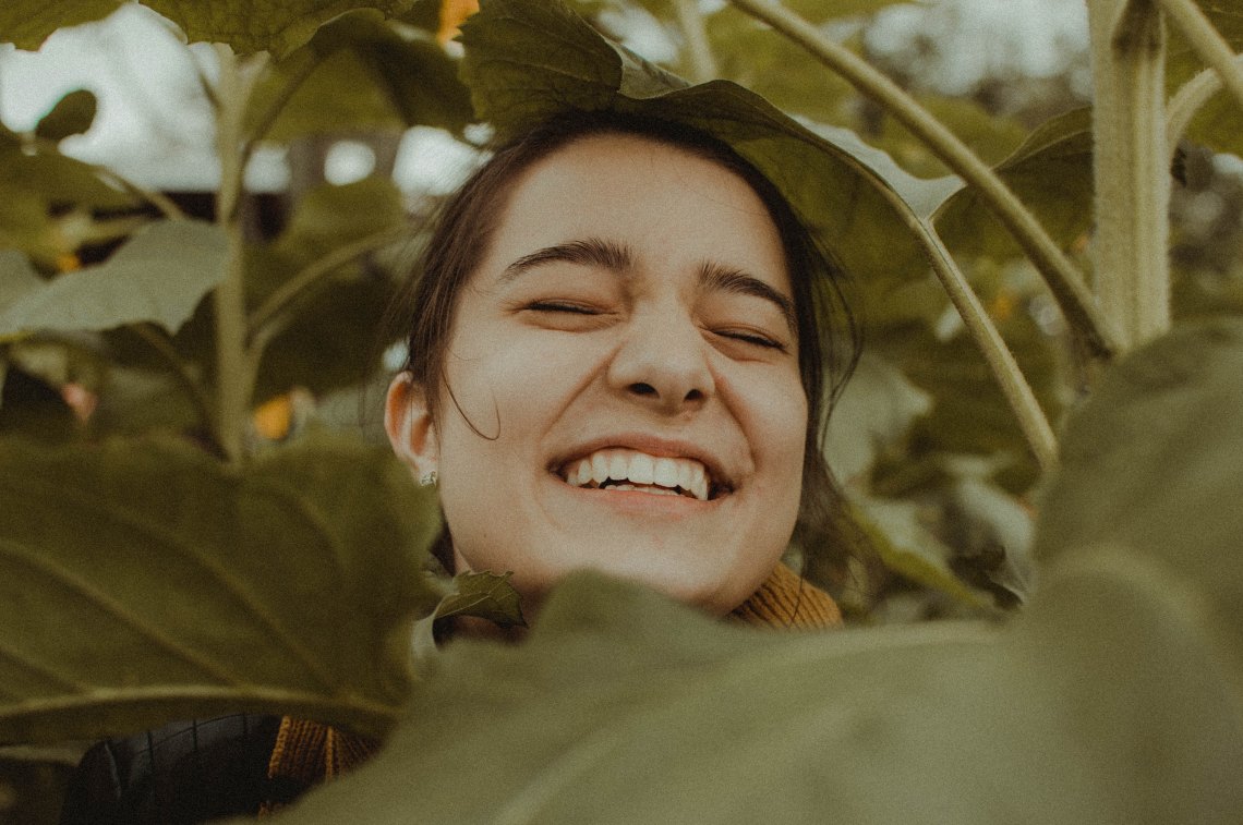 girl laughing in a bunch of leaves