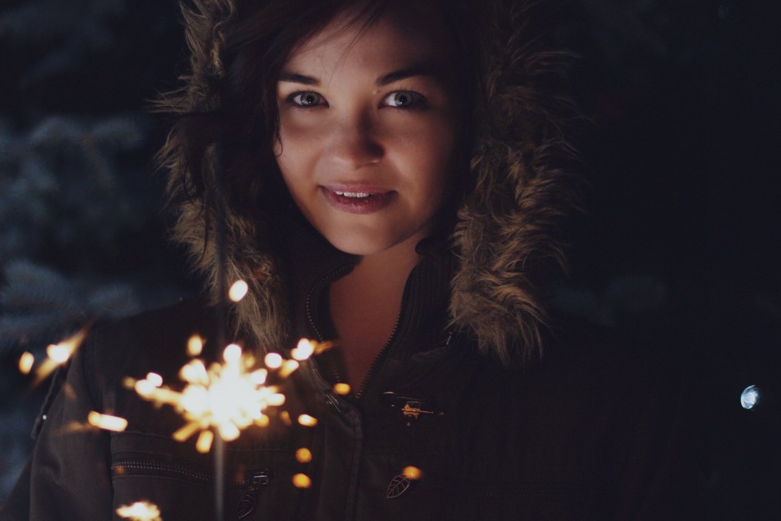 woman holding sparkler in winter