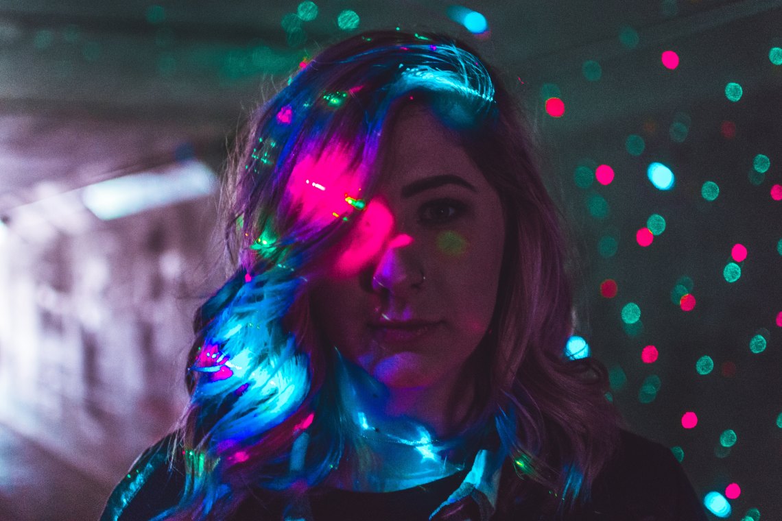 woman with christmas lights behind her and on her face