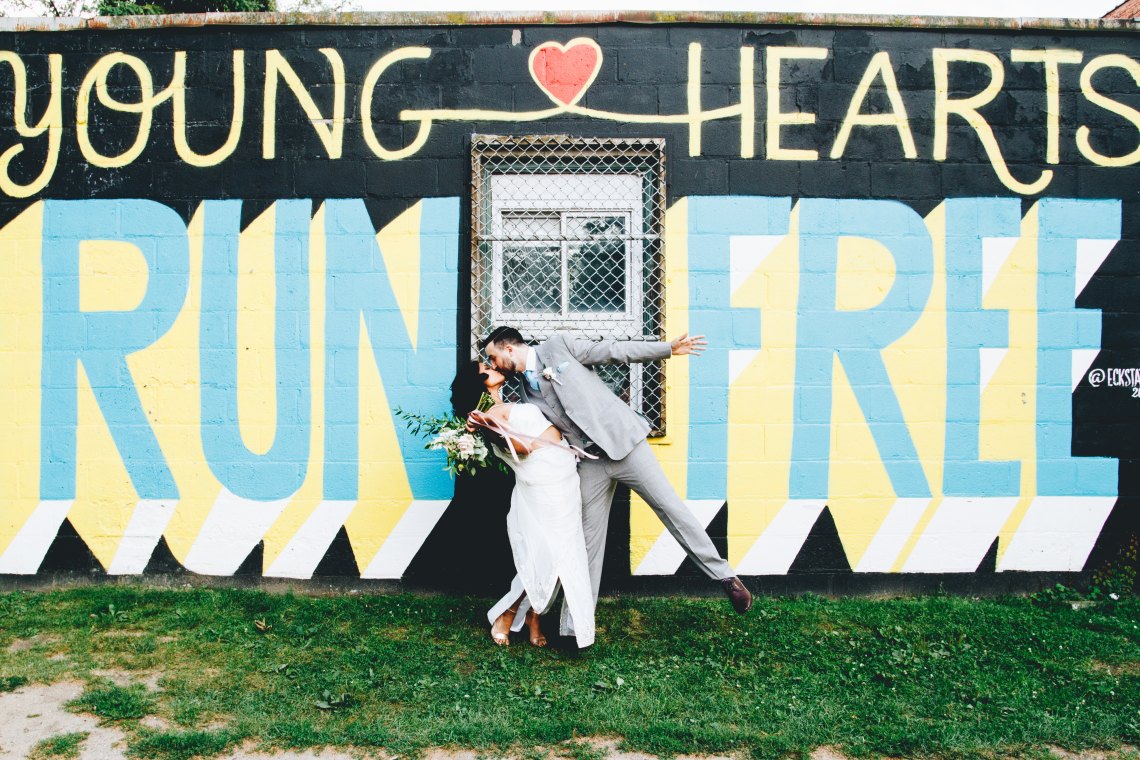 bride and groom kissing in front of word art