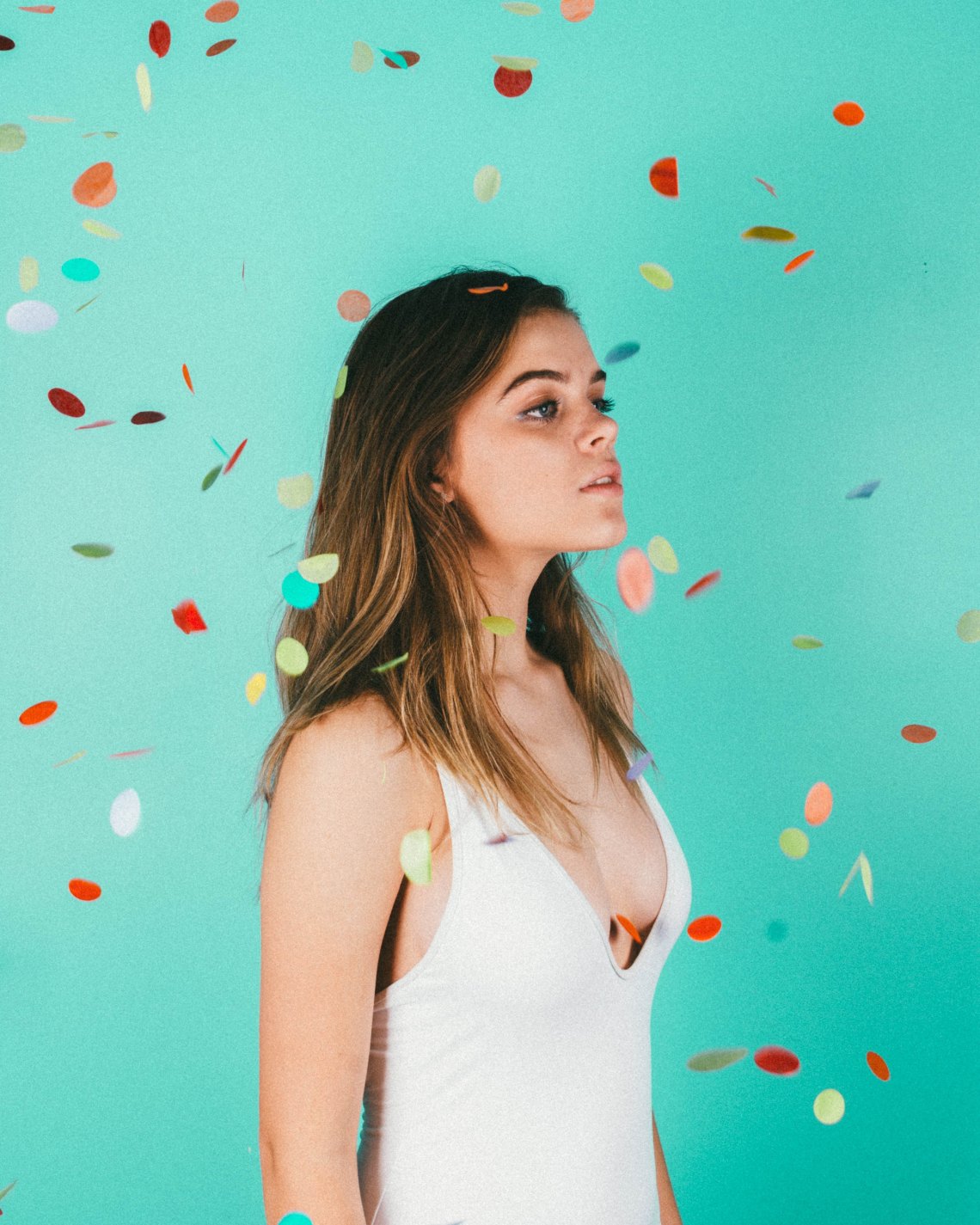 girl standing in front of a teal background with confetti