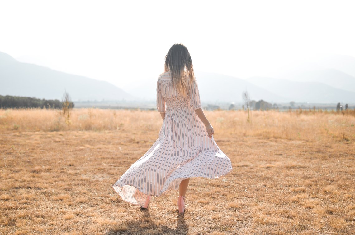 girl twisting her skirt in an open field