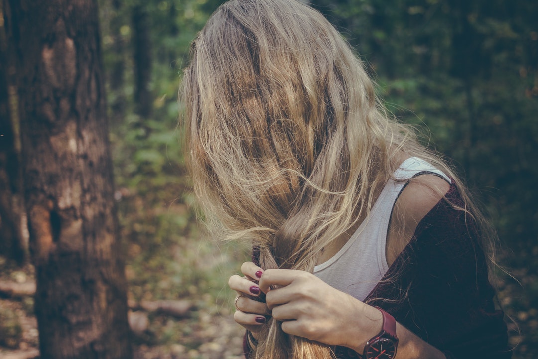 Woman with blonde hair and wearing a watch standing in a forest