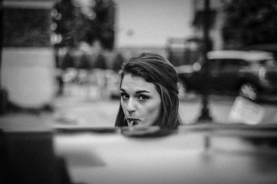 Black and white shot of attractive young woman sucking lollipop in street