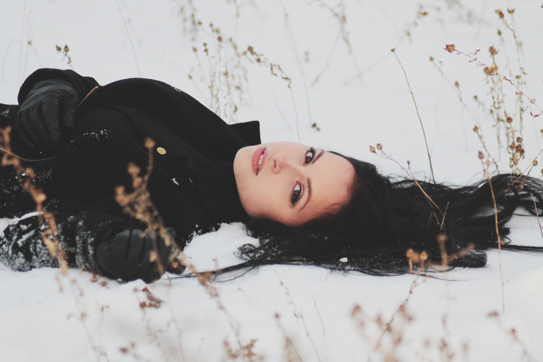 Woman laying down in a field of snow alone