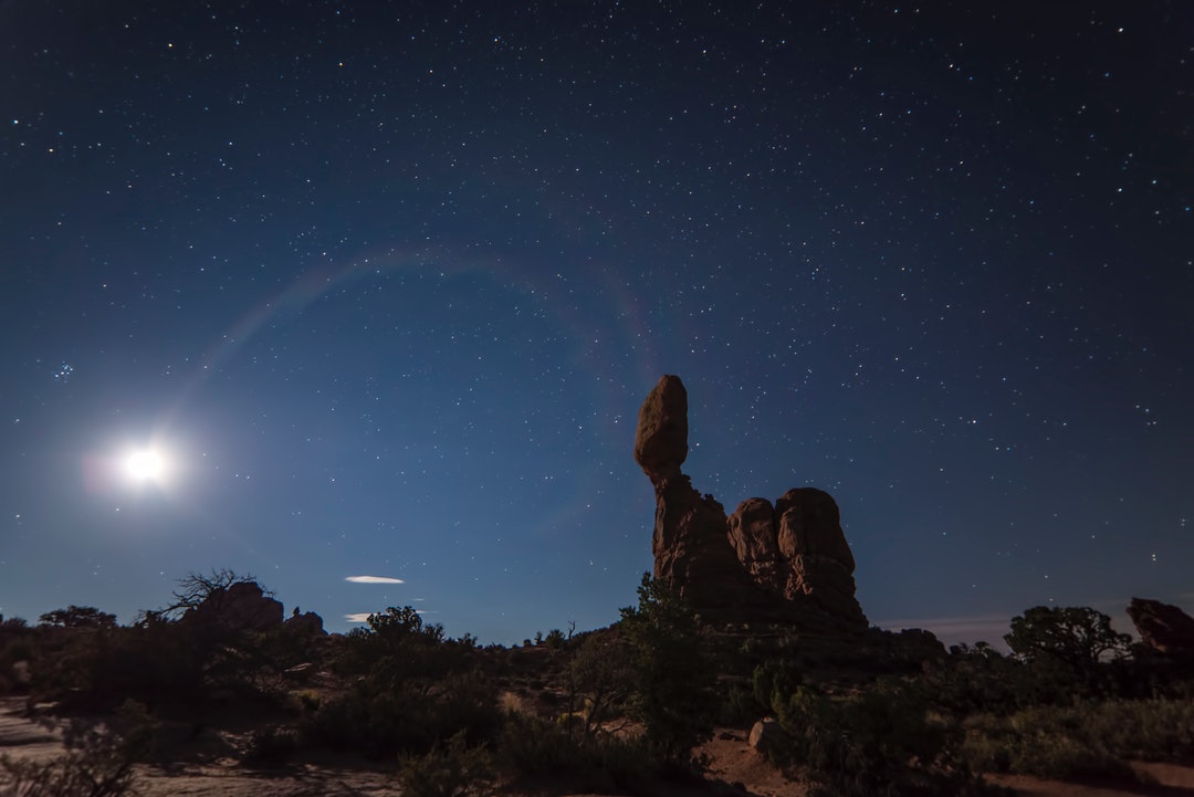 Bright moon over the rock formations on a starry night at Arches National Park
