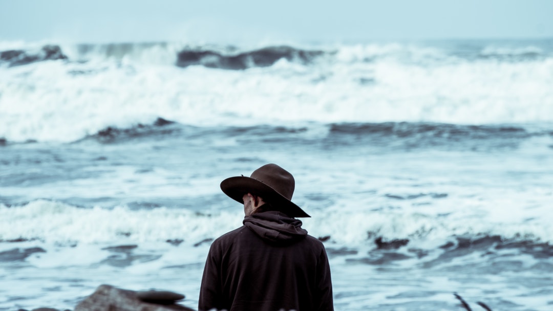 Man with a hat by the rough ocean at Ruby Beach