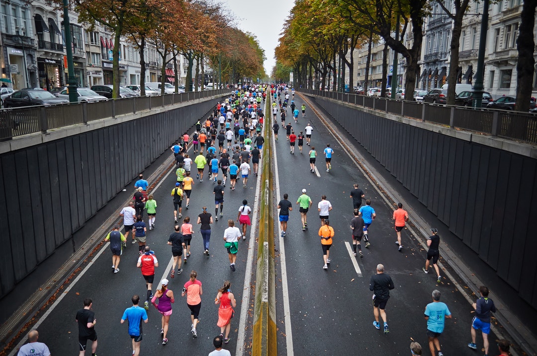 A large group of people running in a marathon in the middle of a street in Brussels