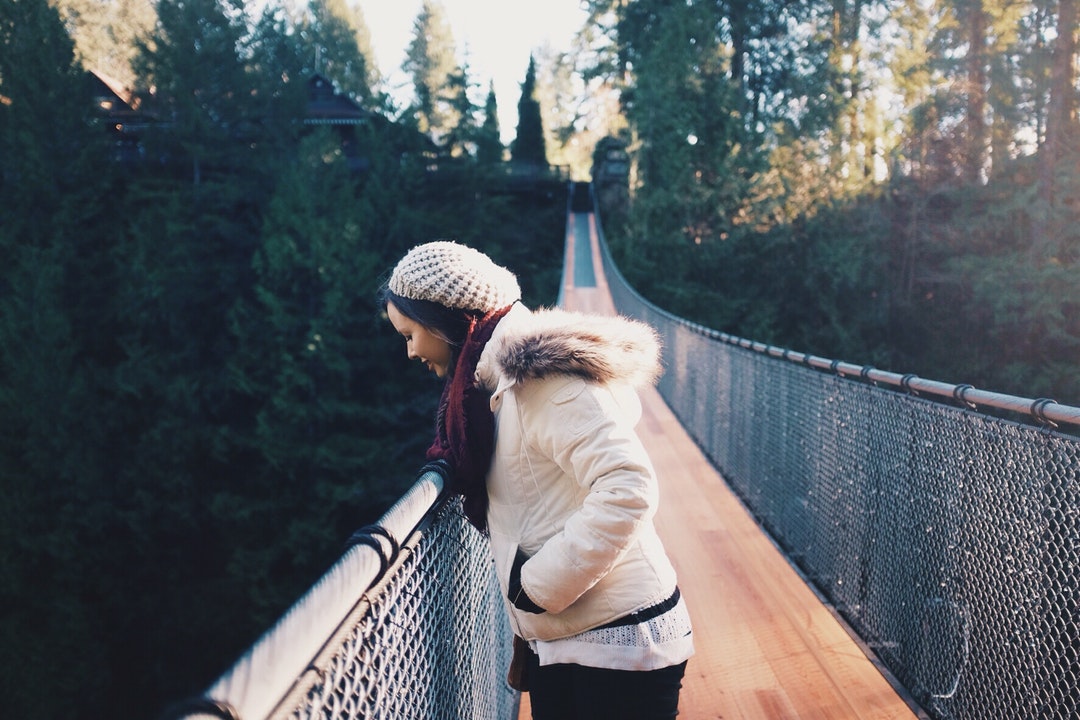 woman standing on brown bridge while looking down during daytime