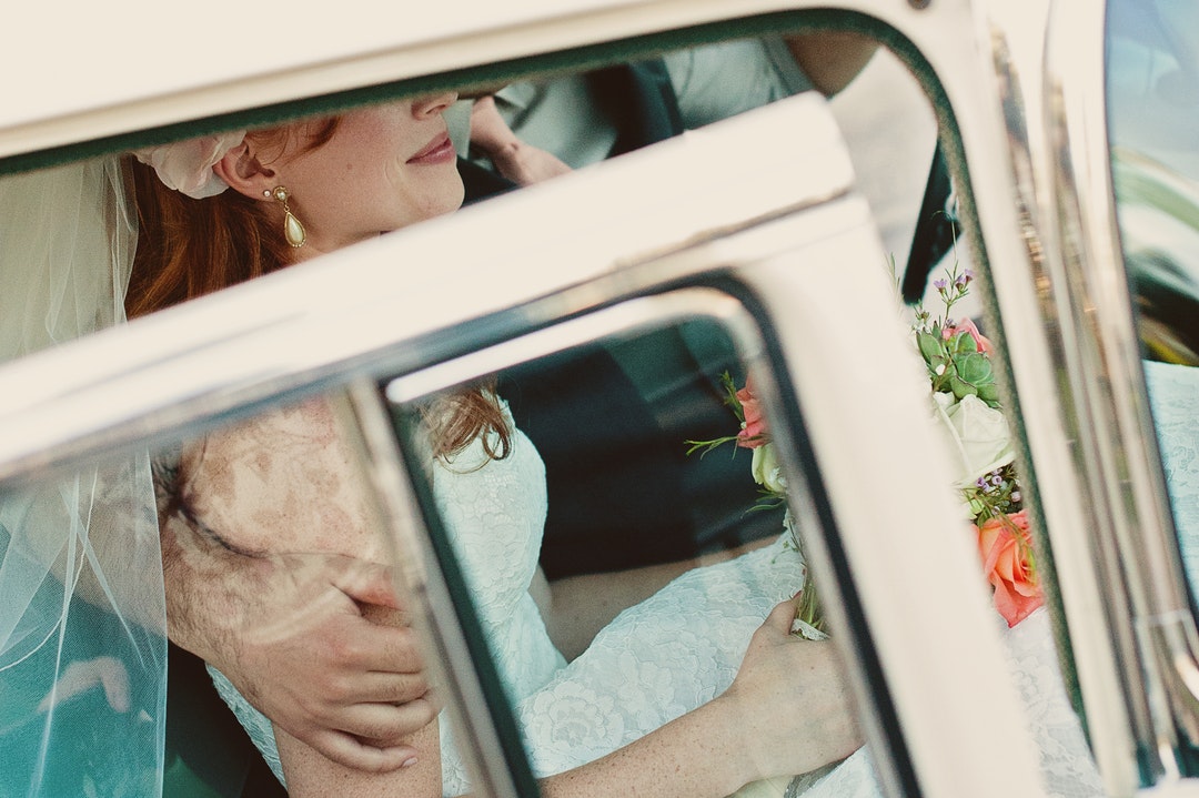 Bridal couple inside a car prepares for their honeymoon