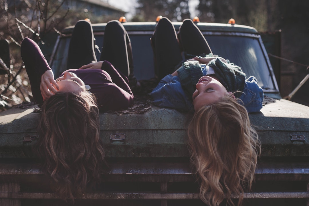 Teens girls lying on the hood of the old truck.