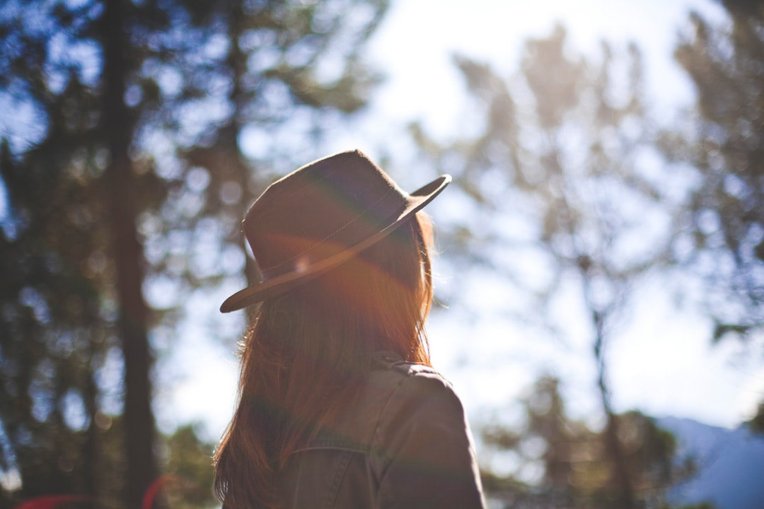 A hazy shot of a woman in a hat on a sunny day