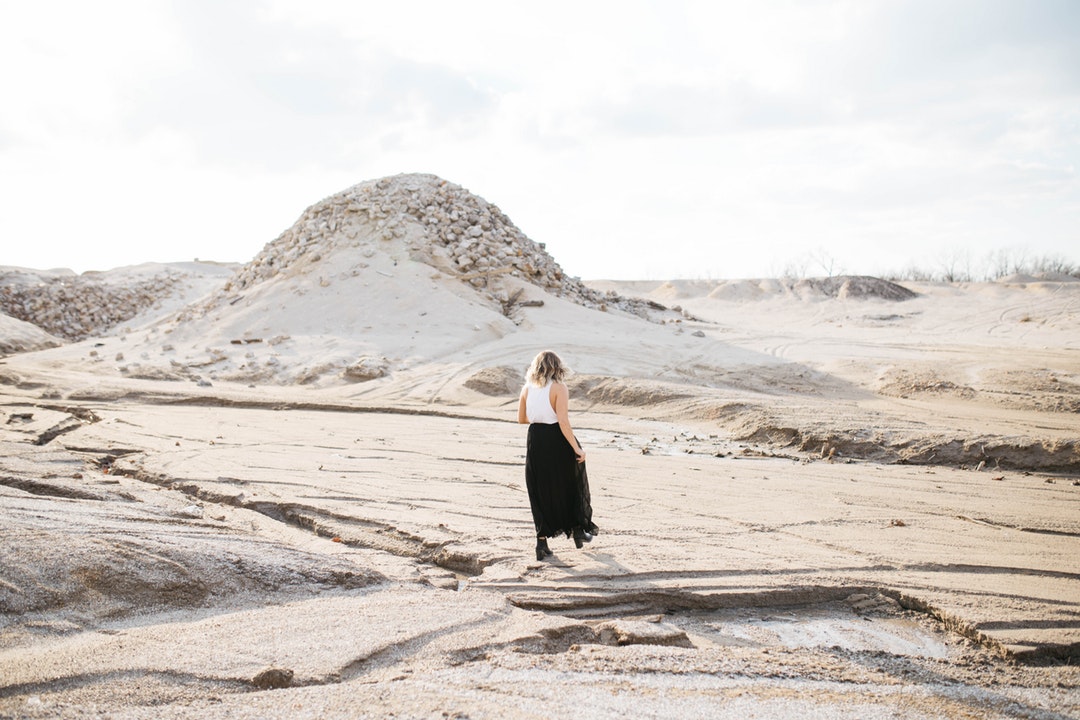 Fashionable woman walks alone through dry desert terrain