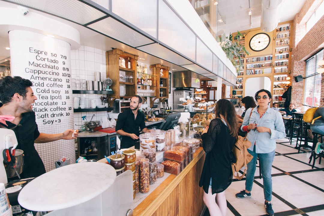 Customers and baristas near the counter in an elegant coffee shop in Tel Aviv