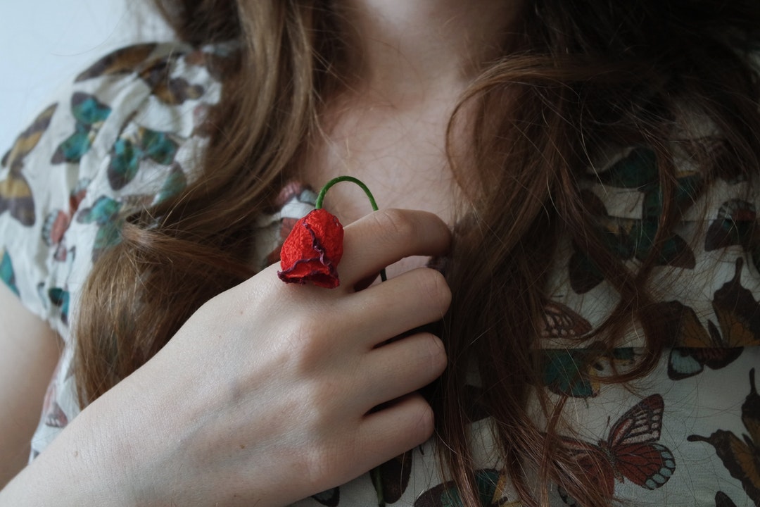 Young woman clutches a withered red rose to her heart
