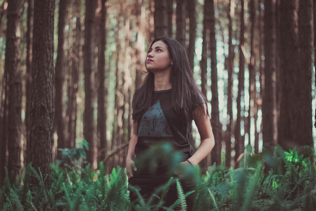 A woman wearing a black t-shirt standing in the forest