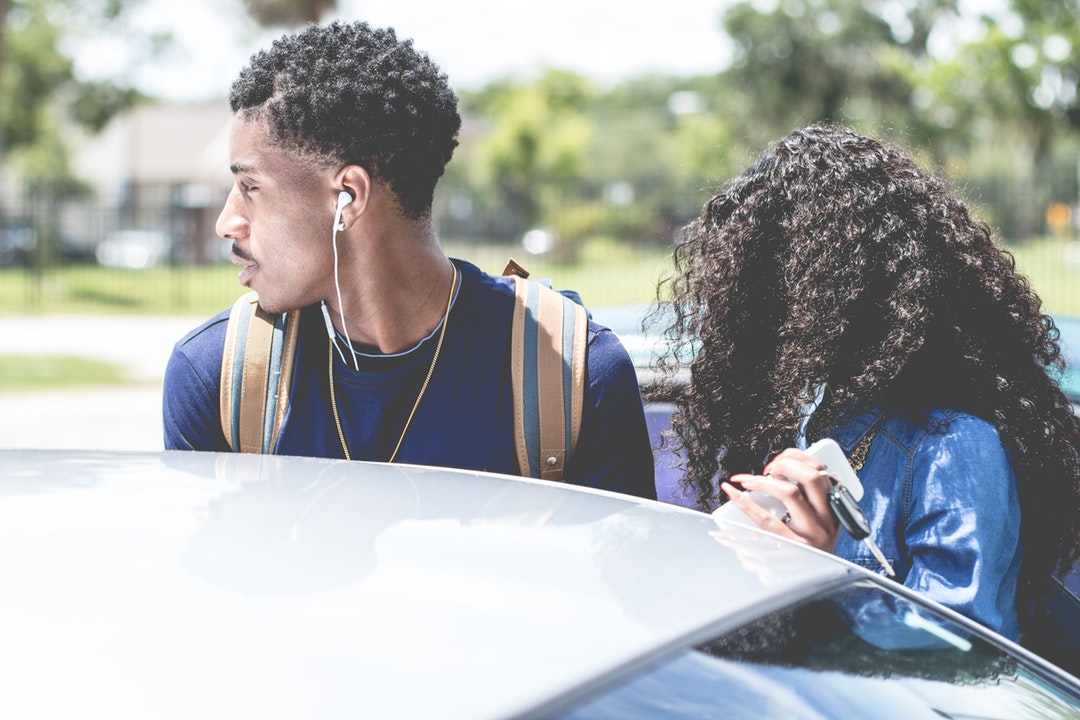 Young fashionable couple with backpack and headphones at Daytona Beach near car