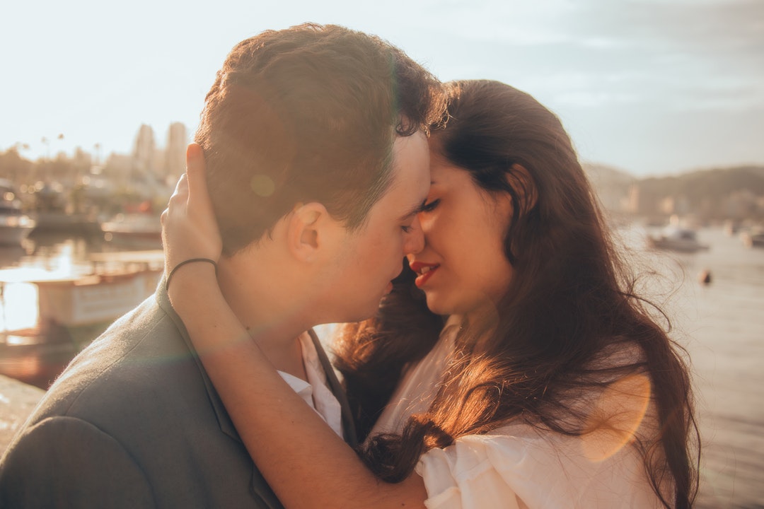 A woman pulls a man into a passionate kiss on sunny Avenida Portugal