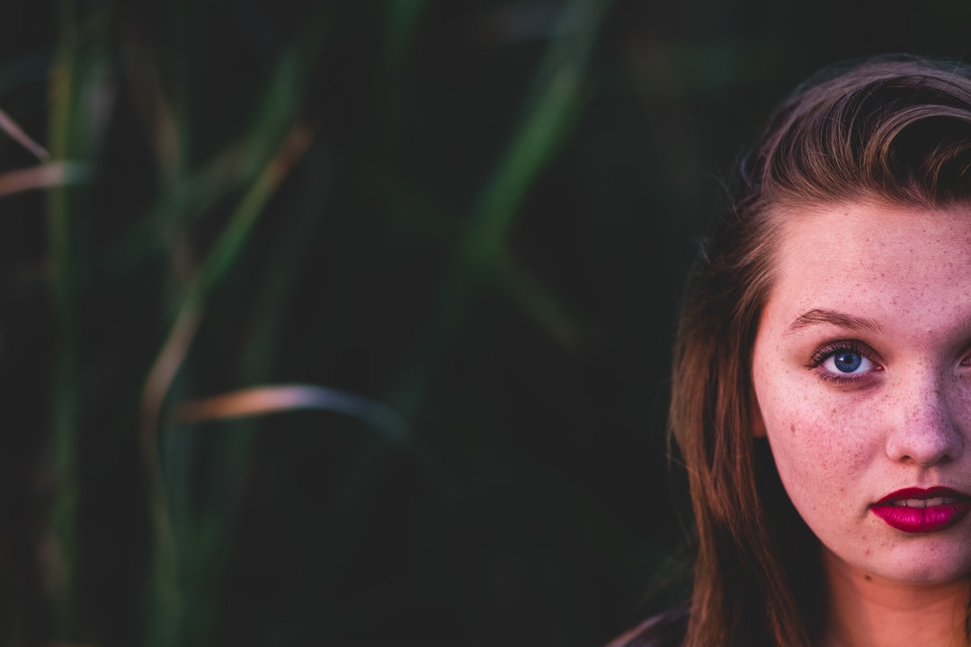 Woman looks up shyly in front of a grassy field