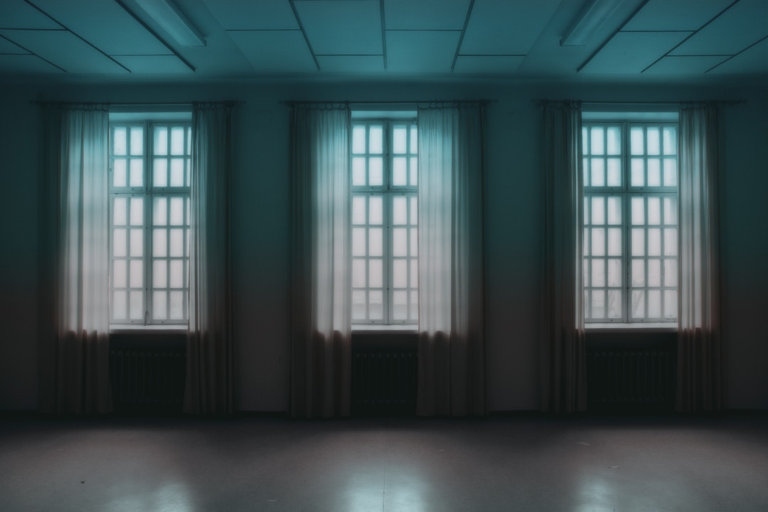 View on the foggy outside from a three high white window dark empty room