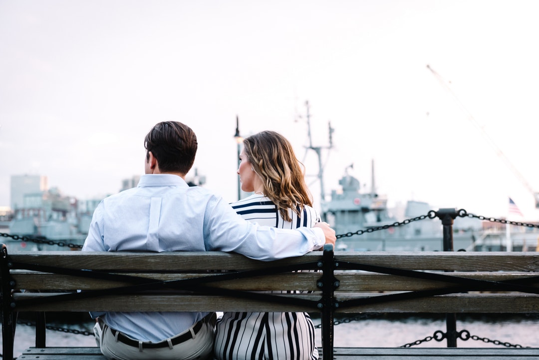 Couple sitting together on a bench by a Boston marina