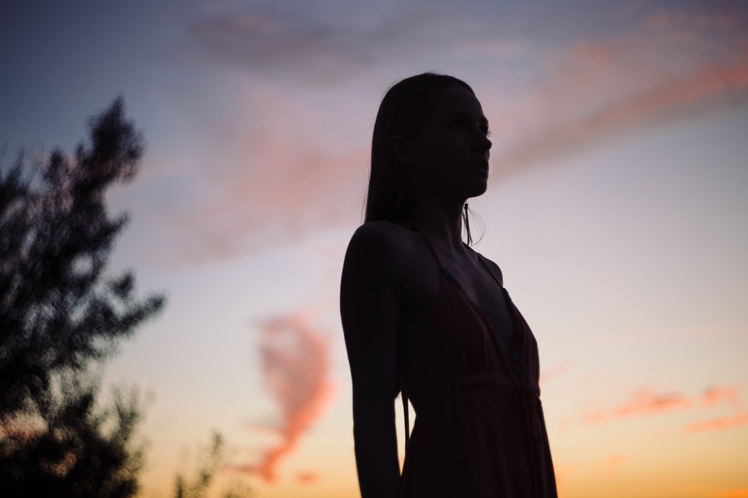 Silhouette of woman with long hair standing during sunset in Olsztyn