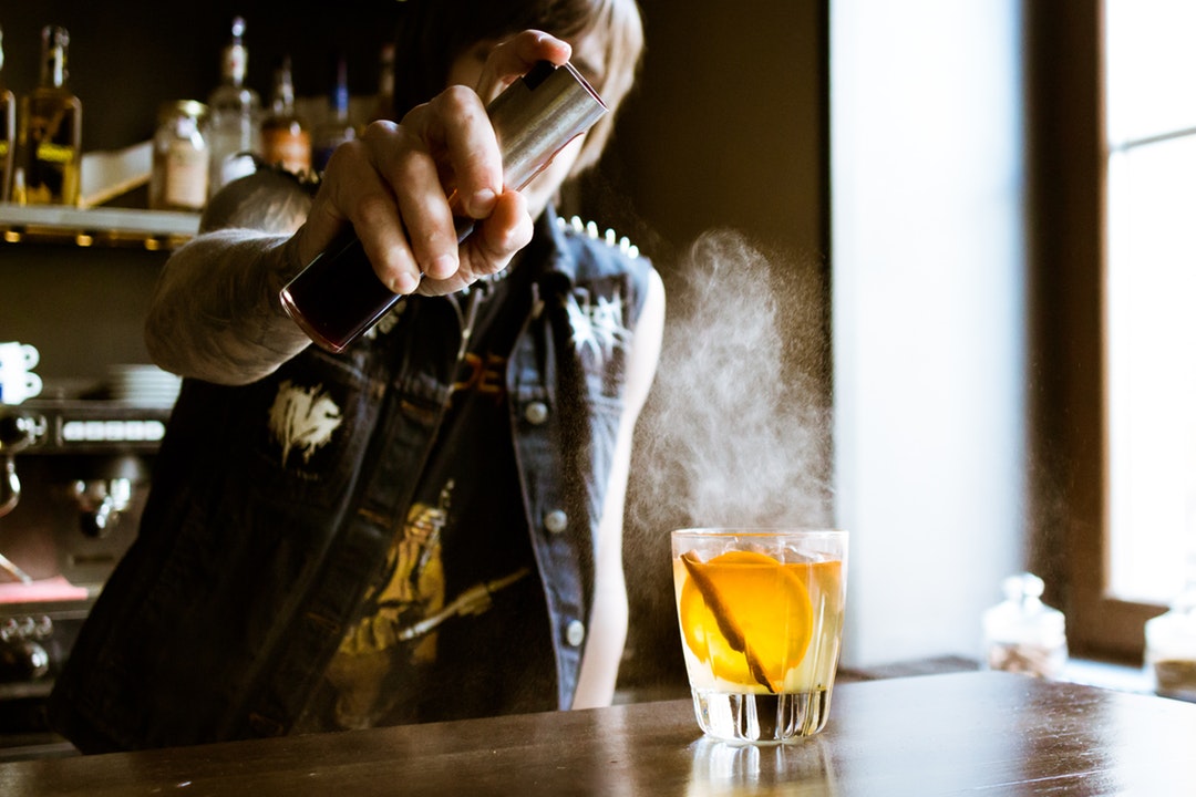 A bartender spraying an a whiskey drink with cocktail in a bar in Vozdvyzhensky